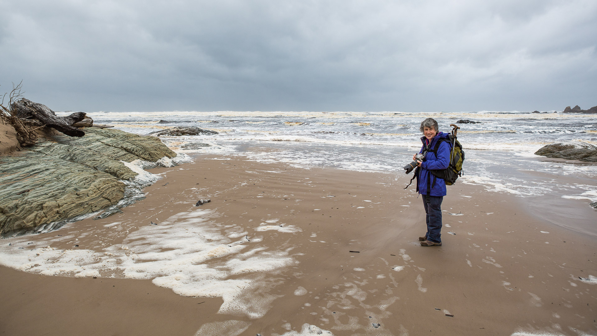 a female photographer standing on the beach of Pieman Heads, a rugged coastline of takayna / The Tarkine